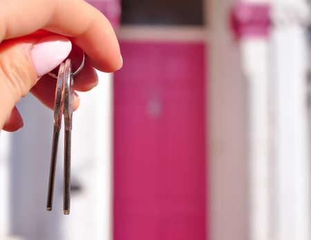 Womans hand with metal keys on blurred background with house. High quality photoの写真素材