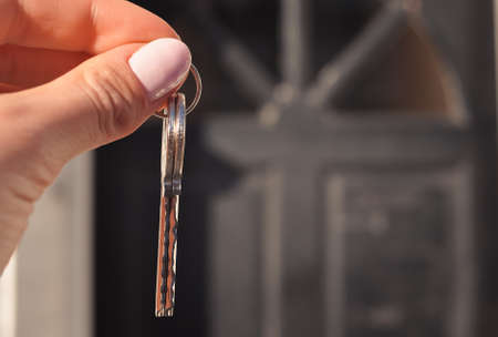 Womans hand with metal keys on blurred background with house. High quality photoの写真素材