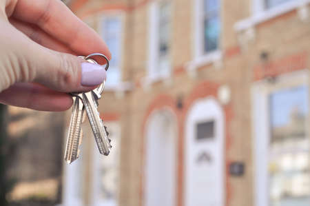 Womans hand with metal keys on blurred background with house. High quality photoの写真素材