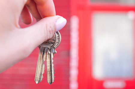 Womans hand with metal keys on blurred background with house. High quality photoの写真素材