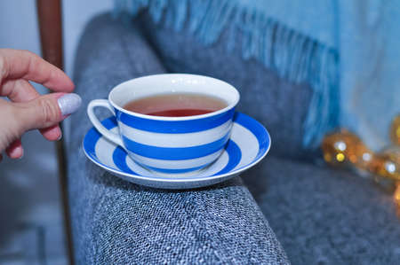 close up of cup of black tea with blue stripes at home ,teatime and relax