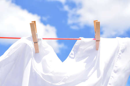close up of washed linen hanging on red rope with clothepins outside.の写真素材