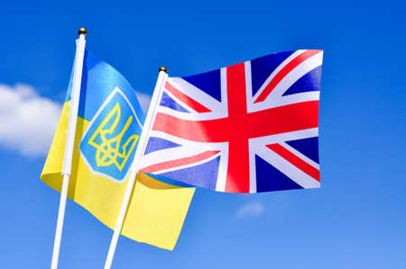 Ukrainian and british flags in the blue sky close up