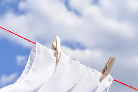 close up of washed linen hanging on red rope with clothepins outside.の写真素材