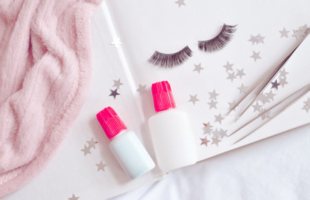 Equipment for eyelash extensions in beauty salon, glue, pink tweezers, strip lashes, flatlay . High...