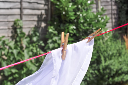 close up of washed linen hanging on red rope with clothepins outside.の写真素材