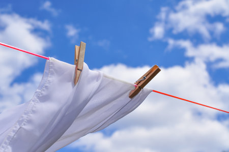 close up of washed linen hanging on red rope with clothepins outside.の写真素材