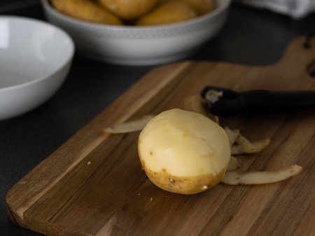 raw potatoes with peeled skin on the wooden desk on the table. High quality photoの写真素材
