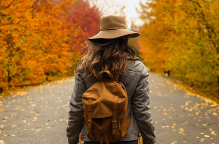 young woman walking in autumn park with lots of yellow and golden leaves.の素材