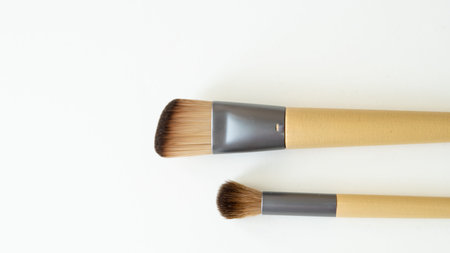 Wooden organic makeup brushes on white backdrop. Eco-friendly, sustainable beauty tools.