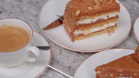 A cup of coffee with milk and a tasty cake on a table in a cozy cafe, perfect for a breakの写真素材
