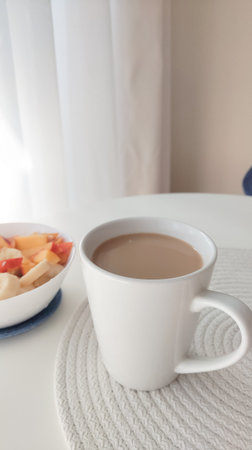 a bowl of oat meal and cup of coffee with milk on the white table in the morning,vegan breakfastの写真素材