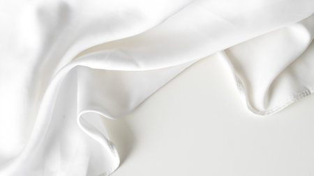 Crumpled white silk fabric background with soft folds and delicate textureの写真素材