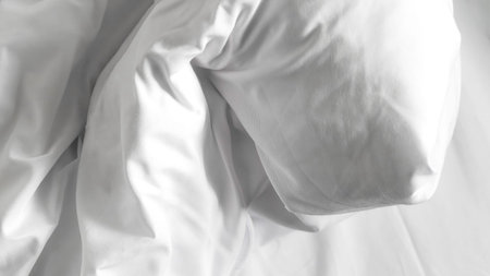 White bedsheets with fluffy blanket on simple background, soft texture and comfort.