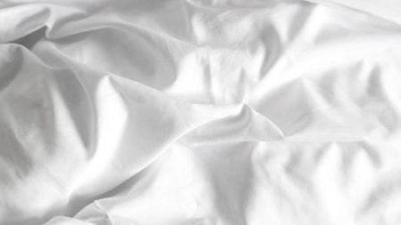 Clean white bedsheets and folded blanket on solid background, home decor concept.