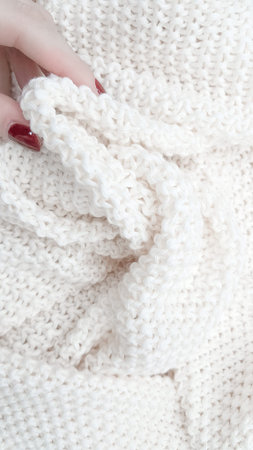 A soft, textured white knitted plaid background with intricate patterns and cozy appeal. High...
