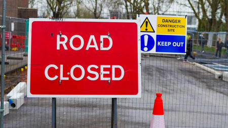 road closed red sign on an urban street with visible construction barriersの写真素材