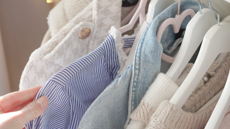 Cozy autumn outfits hanging in a wardrobe, highlighting earthy tones and texturesの写真素材
