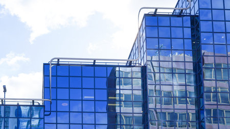 High rise blue glass office building reflecting sun and city structures