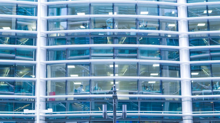 Towering blue glass skyscraper reflecting sky and city buildings below.