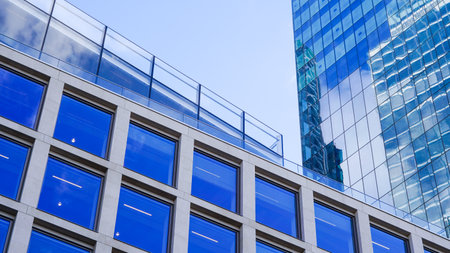 Contemporary high rise building with blue glass reflecting city surroundingsの写真素材
