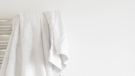 Fresh white towel on a modern heater, elegant home decor, soft and cozyの写真素材