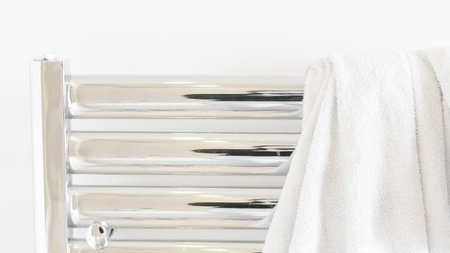 Clean white towel draped over a metal heater, minimalist bathroom aestheticの写真素材