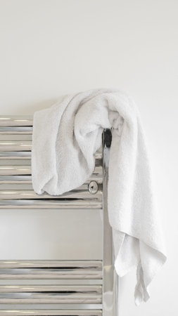 Soft white towel on a heated towel rail, modern bathroom interior, minimalismの写真素材