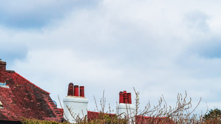A simple composition of a red house roof with a chimney under a blue skyの写真素材