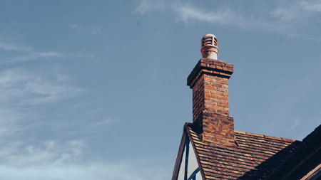 A rustic brick chimney on a classic English countryside home roof.の写真素材