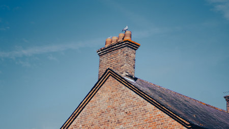 A rustic brick chimney on a classic English countryside home roof.の写真素材