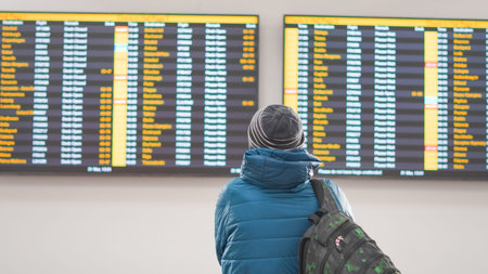 Passenger waiting for flight information at the airport while looking at the board.
