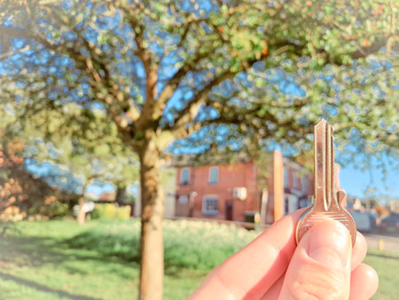 A real estate agent holding a key, symbolizing security, success, and ownership.の写真素材