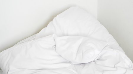 White duvet and pillow on cozy bed showing hotel calm and spa ambiance.の写真素材