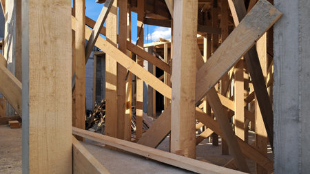 Timber framing on construction site under bright sunlight and blue sky