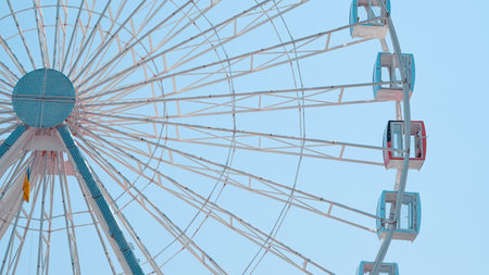 Close view of Ferris wheel cabins on sunny sky background in park setting.の写真素材