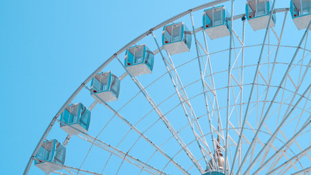 Close view of Ferris wheel cabins on sunny sky background in park setting.の写真素材