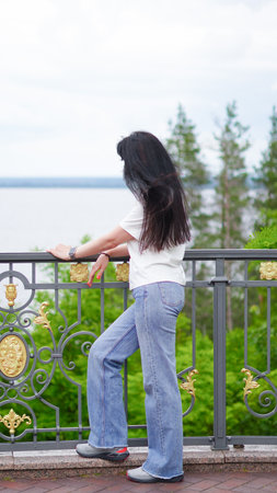 Brunette woman stands back to camera enjoying peaceful natural landscape view.の写真素材