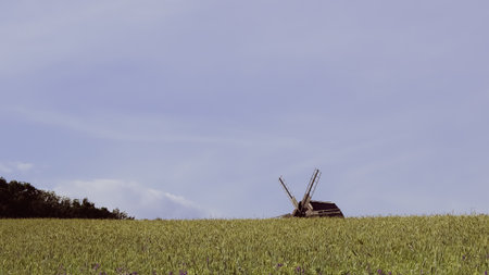 Old countryside windmill in motion with visible blades and wooden frame.の写真素材