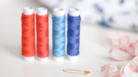 Colorful threads and tape arranged neatly on white background for crafting.の写真素材
