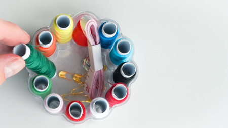 Colorful sewing threads, safety pins, and tape measure on white background.の写真素材