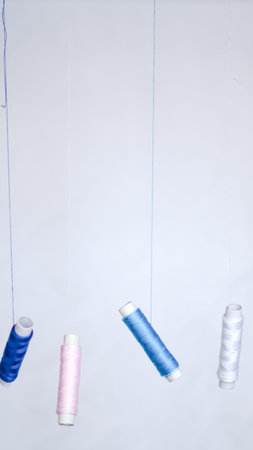 Neatly arranged sewing threads with measuring tape on flat white surface.