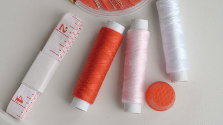 Flat lay of sewing tools including threads, pins and measure tape for DIY.の写真素材