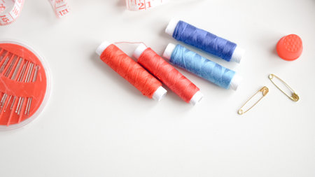 Colorful threads and tape arranged neatly on white background for crafting.の写真素材