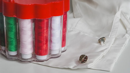Sewing composition with threads, pins, and tape on neutral white surface.の写真素材