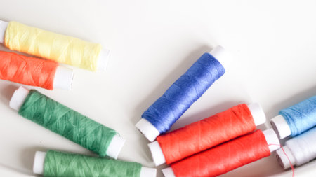 Colorful sewing threads with measuring tape on clean white background.