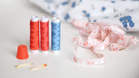 Colorful sewing threads with measuring tape on clean white background.