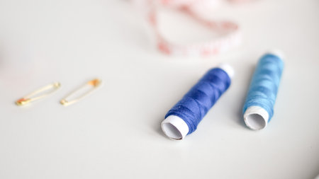 Colorful sewing threads with measuring tape on clean white background.の写真素材