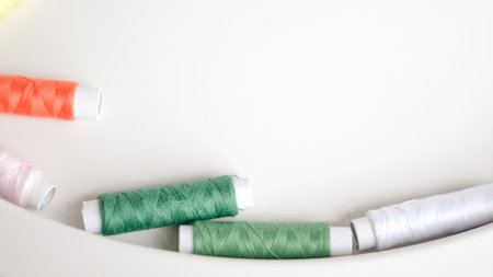 Soft home sewing scene with colored thread spools and gentle fabric.の写真素材