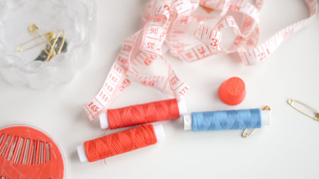 Colorful threads and tape arranged neatly on white background for crafting.の写真素材